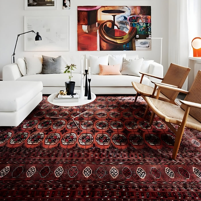 A cozy living room featuring a plush rug on the floor, a comfortable couch adorned with pillows, and a stylish coffee table. The room is well-decorated with a lampshade casting soft light, and walls adorned with wallpaper. A vase adds an elegant touch to the space.