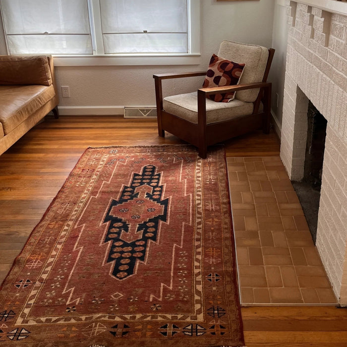 A cozy living room featuring a soft vintage rug on the hardwood floor, a comfortable couch, and a warm fireplace. The interior design includes stylish furniture and neutral-colored walls.