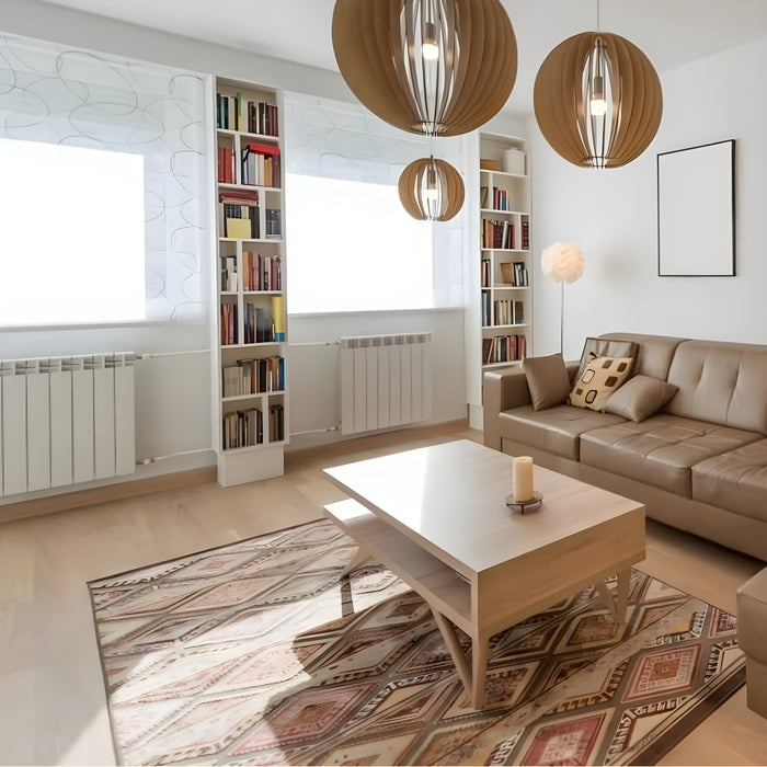 A cozy living room with a vintage rug on the wood laminate floor, a bookcase filled with books, and a coffee table in the center. A studio couch lines one wall, while the space is adorned with pillows and other charming furnishings, adding warmth and character.