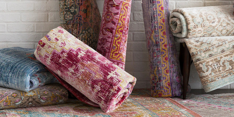 Folded vintage wool rugs in various colors, showcasing intricate designs and textures.