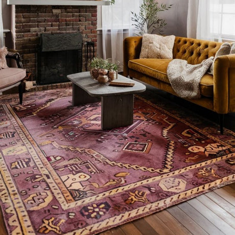 A cozy living room featuring a traditional beige and purple patterned rug laid on the floor, an orange sofa, a fireplace, and modern decor elements.