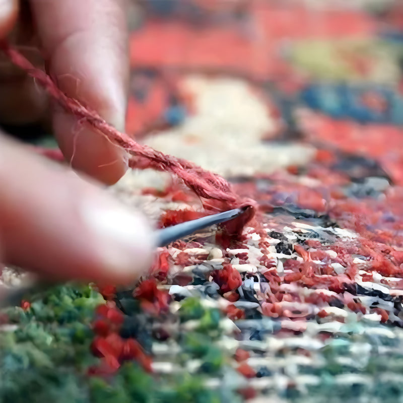 A craftsman repairing a vintage rug with care and precision.