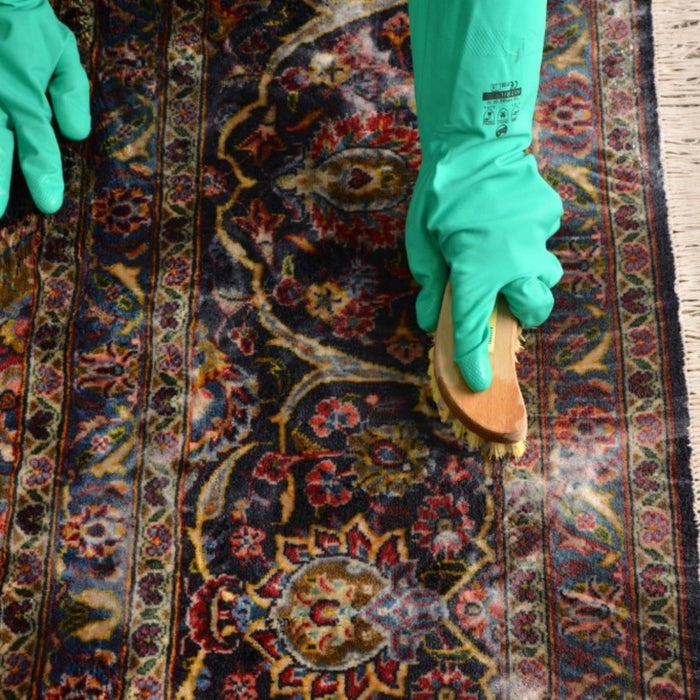 Vintage wool rug being cleaned with a brush, carefully maintaining its texture and quality.