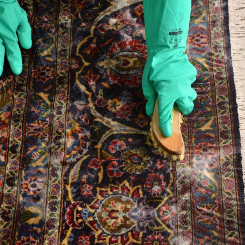 Vintage wool rug being cleaned with a brush, carefully maintaining its texture and quality.